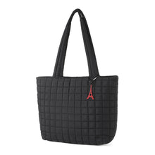 Load image into Gallery viewer, Angled front view of black quilted tote bag with red Eiffel Tower charm