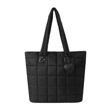 Load image into Gallery viewer, Front view of black quilted tote bag with heart charm accent.