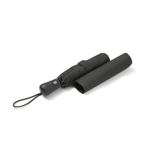 Load image into Gallery viewer, Half-folded view – Black compact umbrella partially folded with sleeve placed alongside.