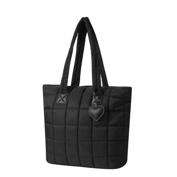 Black quilted tote bag with padded straps and heart charm, angled side view.