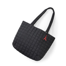 Load image into Gallery viewer, Flat lay of black quilted tote bag with red Eiffel Tower keychain charm
